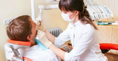 jovem dentista a atender paciente