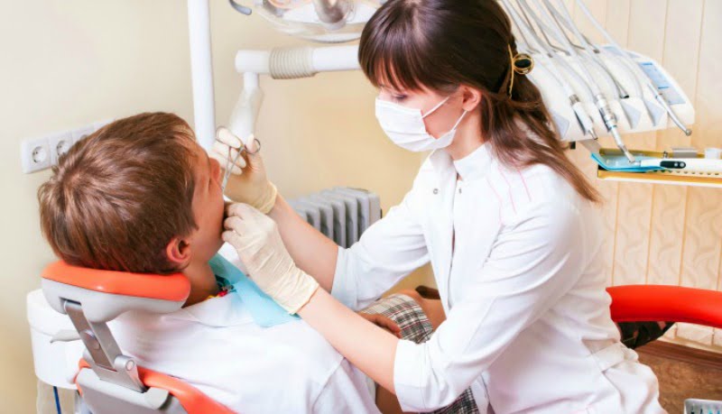 jovem dentista a atender paciente